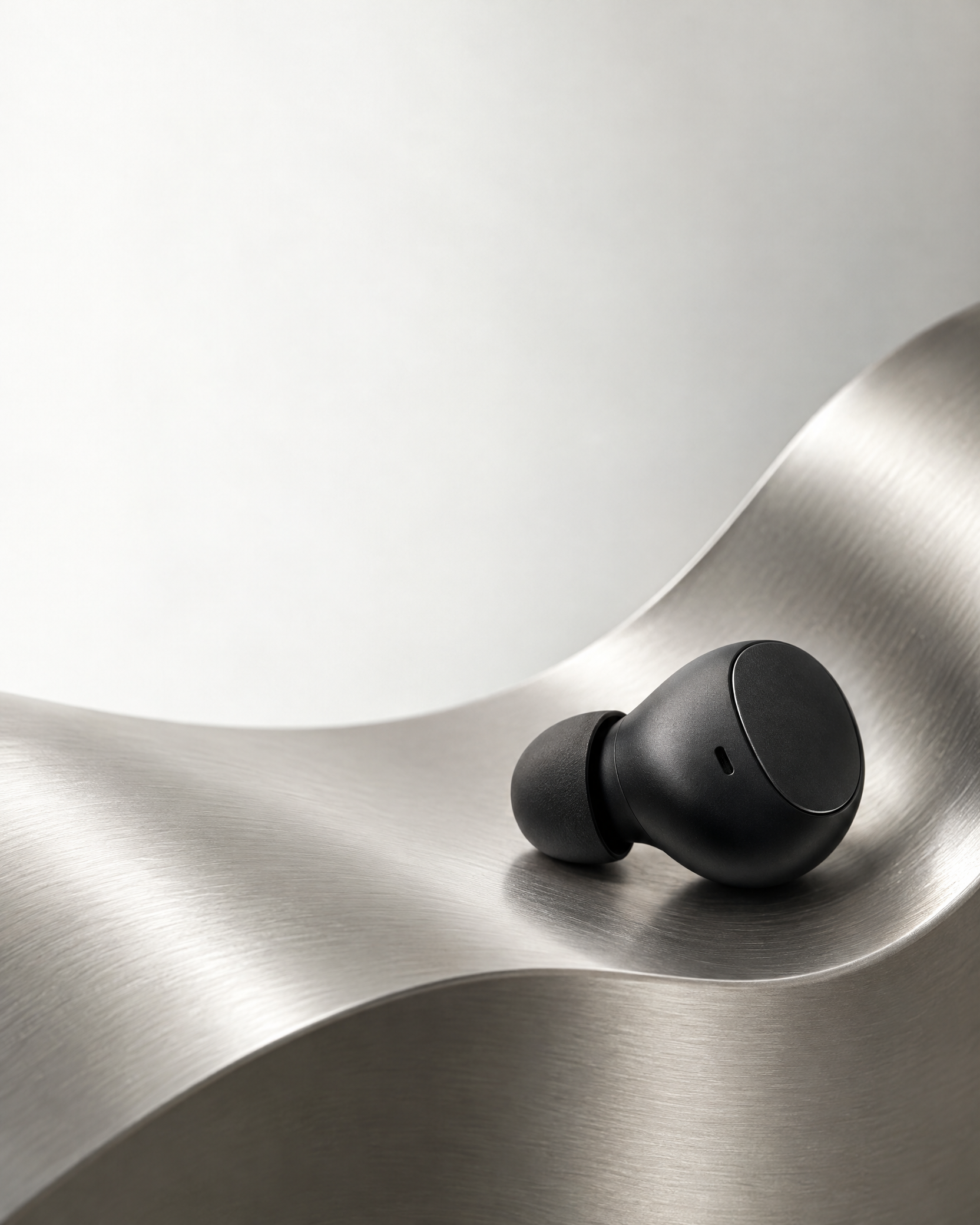 Earbud premium preto em superfície escultural prateada